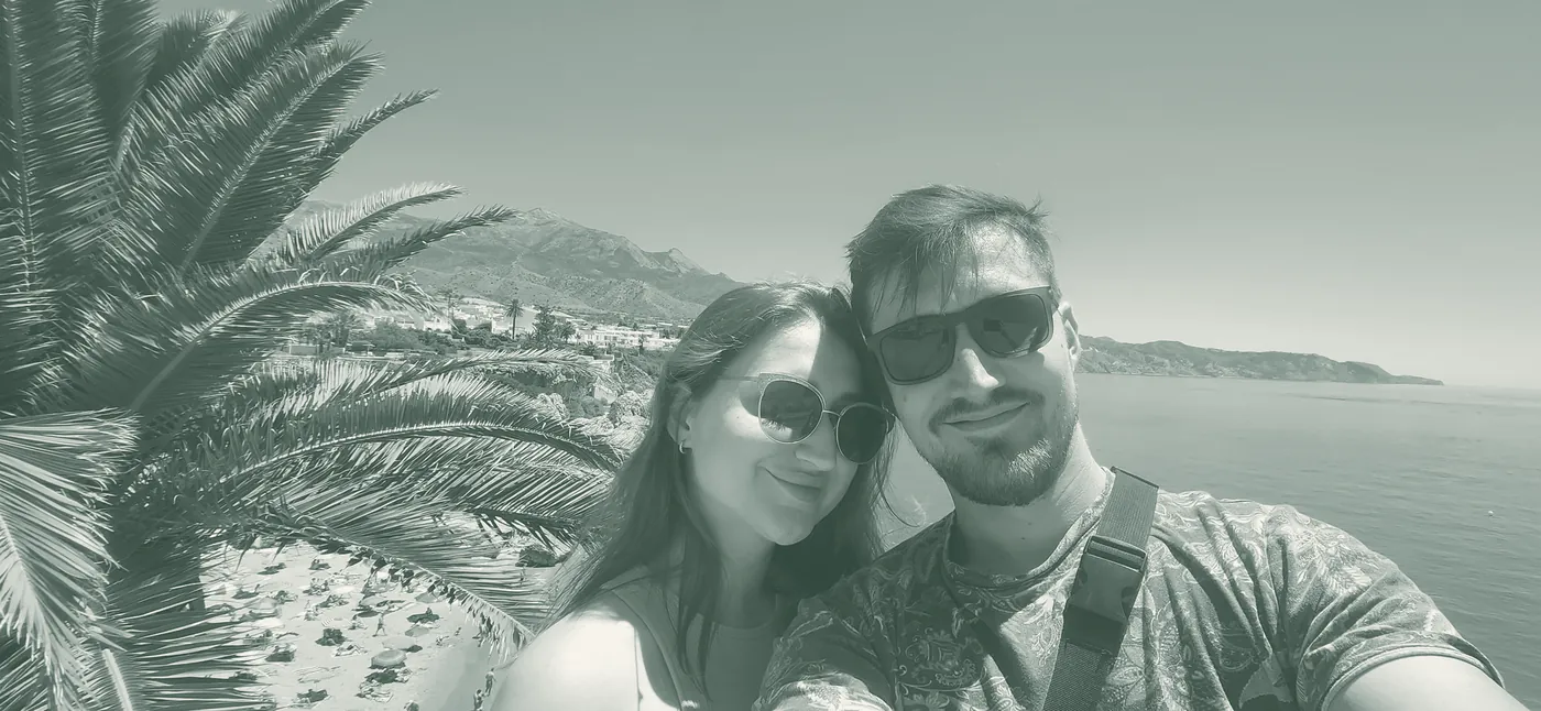 Selfie von Alona und Jan am Balcón de Europa in Nerja, dahinter Palmen, Strand und Meer